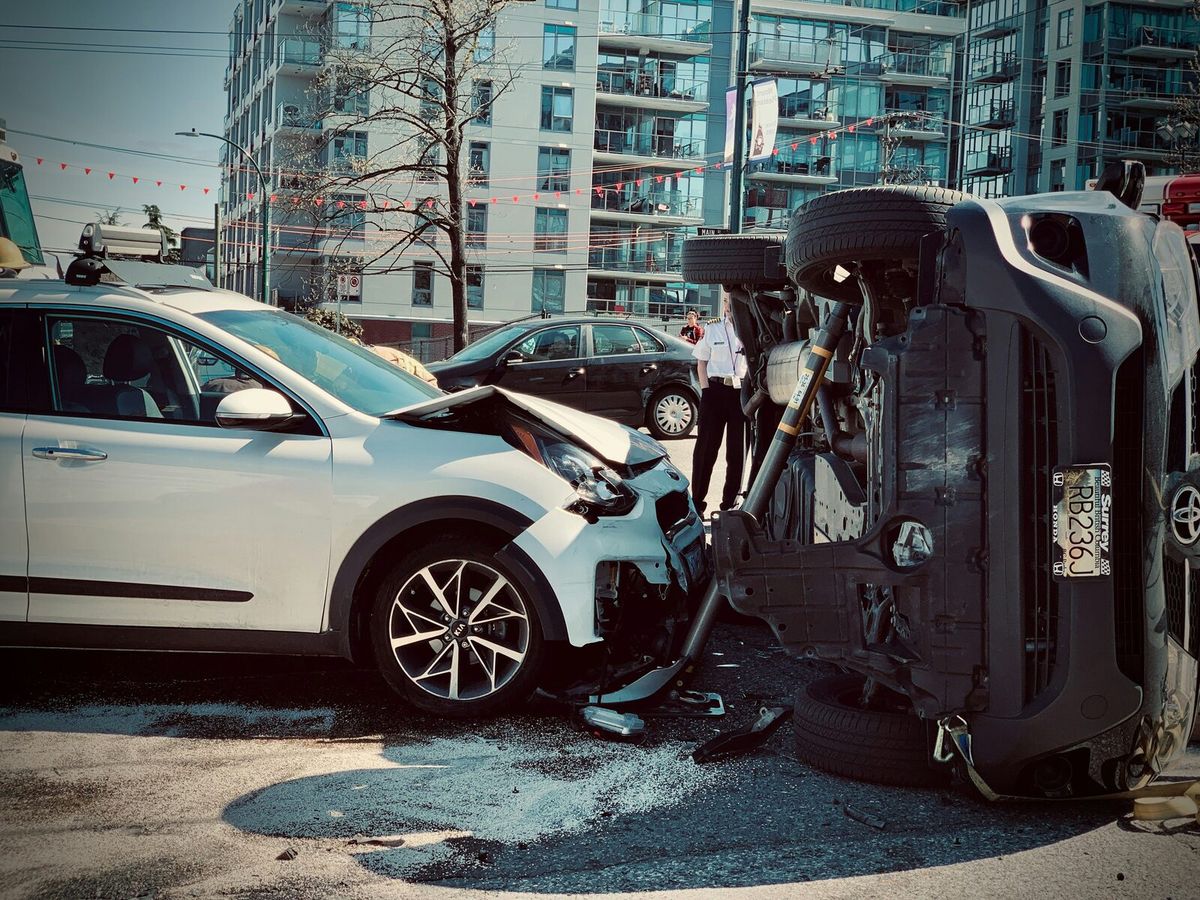 Two cars after a collision, one overturned, on a city street