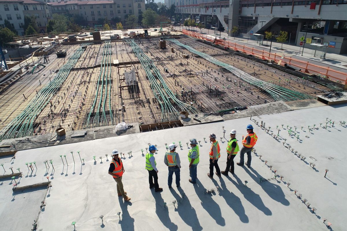 Construction workers in safety gear on a large building site