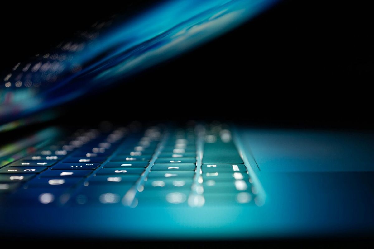 A laptop keyboard glowing blue in a dark room