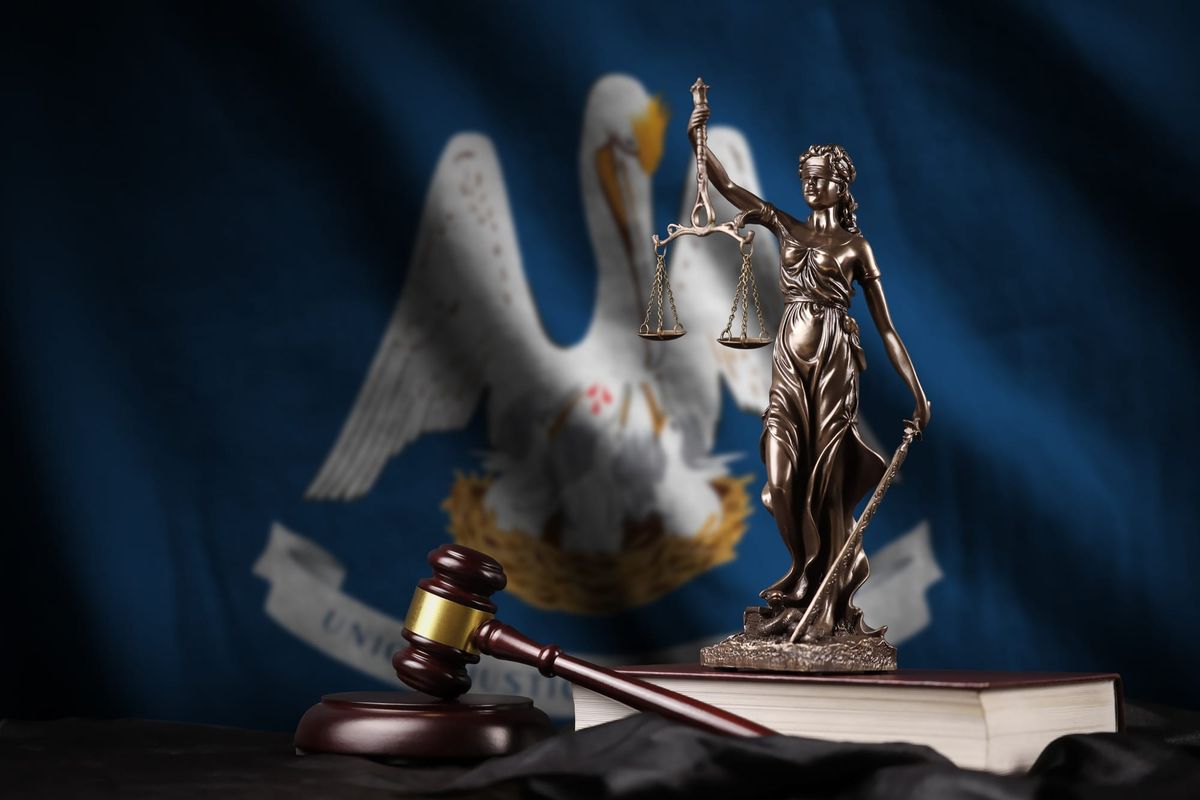 Louisiana state flag with scales of justice on top of legal book with gavel.