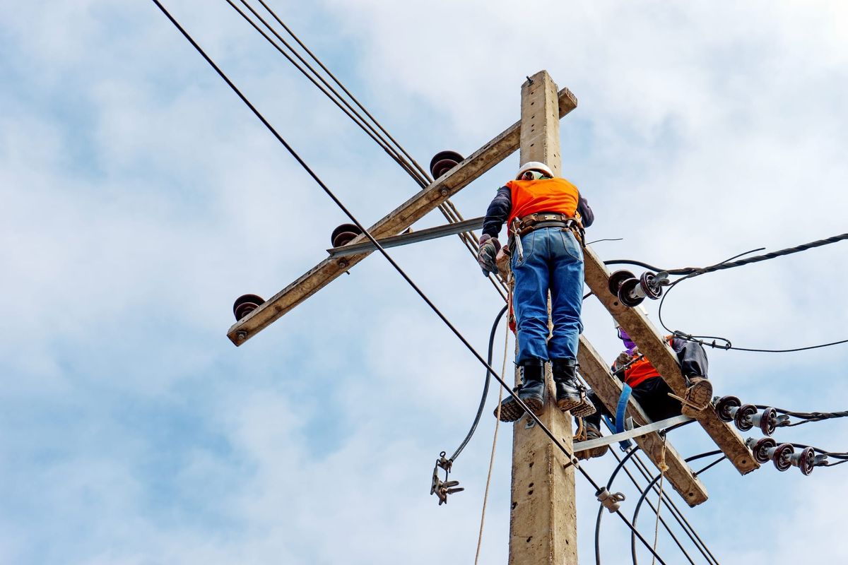 Two electrical line workers repairing powerlines.
